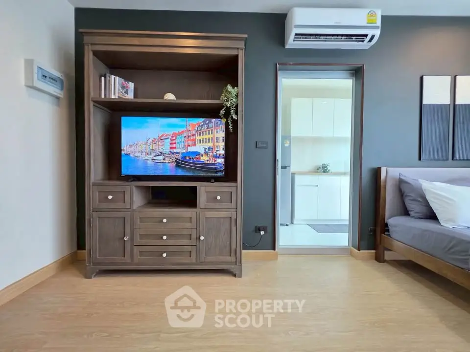 Modern living room with wooden flooring, stylish TV cabinet, and air conditioning unit.