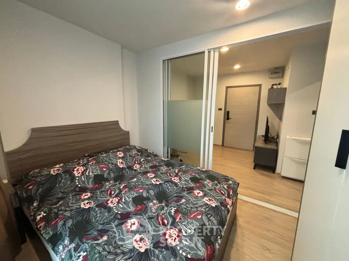 Cozy bedroom with floral bedding and sliding glass doors in modern apartment.