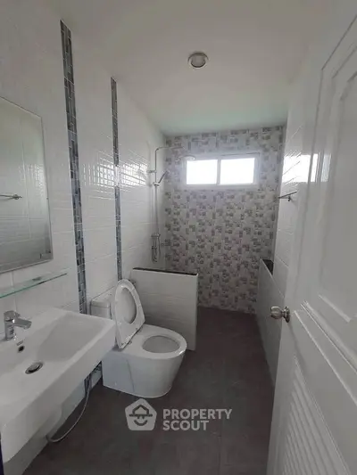 Modern bathroom with sleek design and tiled walls, featuring a shower and toilet.