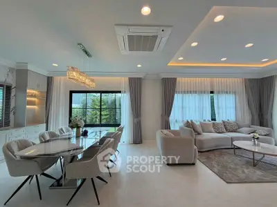 Luxurious open-plan living room with elegant dining area and large windows for natural light.
