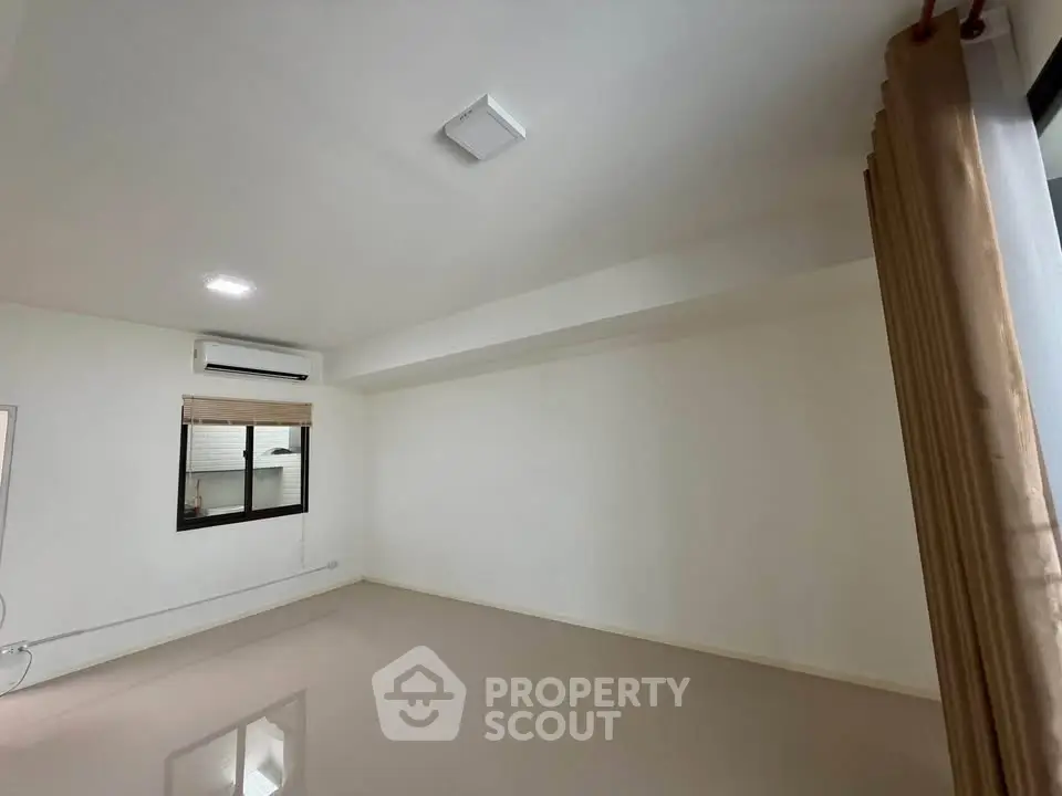 Spacious empty room with large window and air conditioning, perfect for customization.