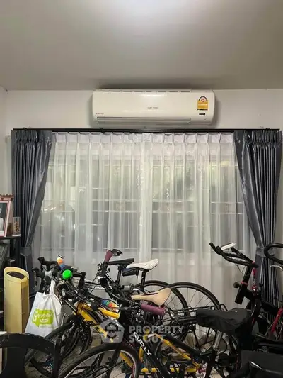 Room with bicycles and air conditioning, featuring large window with curtains, ideal for storage or hobby space.