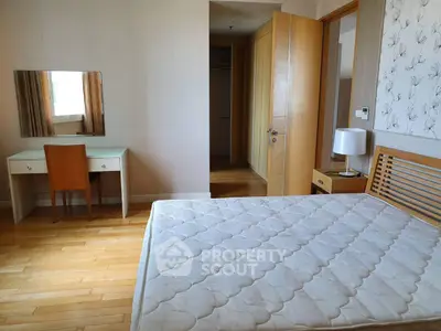 Spacious bedroom with wooden flooring and elegant furniture in modern apartment.