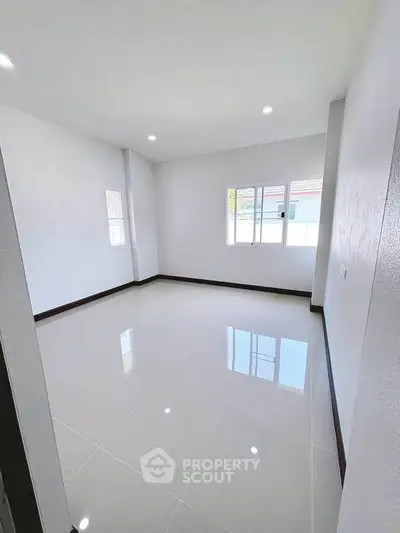 Spacious empty room with glossy tiled flooring and large windows for natural light.