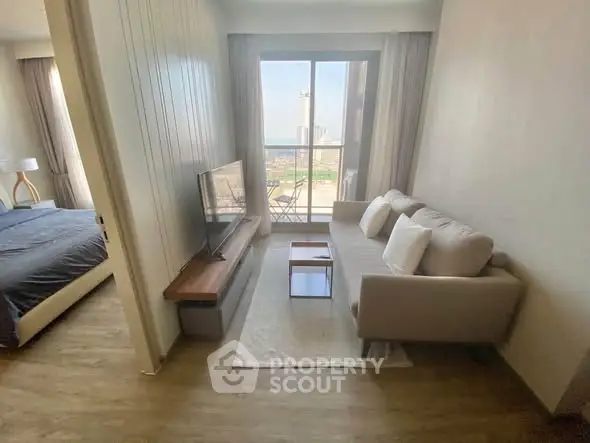 Modern living room with cozy sofa and TV, adjacent to a bedroom with a scenic view.