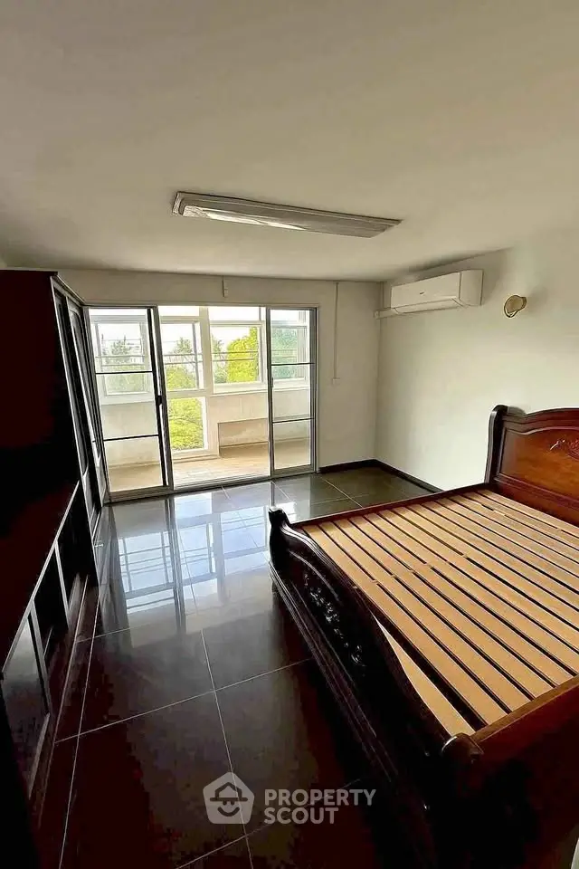 Spacious bedroom with large windows and balcony access, featuring sleek flooring and modern air conditioning.