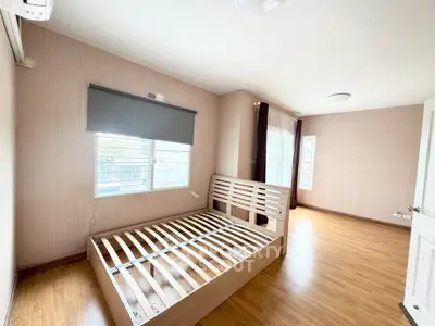 Spacious bedroom with wooden flooring and large windows for natural light.