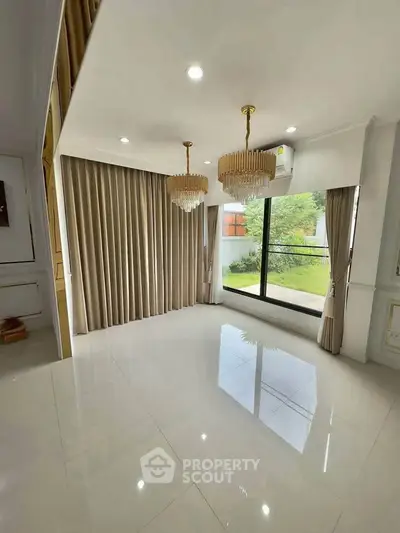 Elegant empty living room with chandeliers and large window overlooking garden