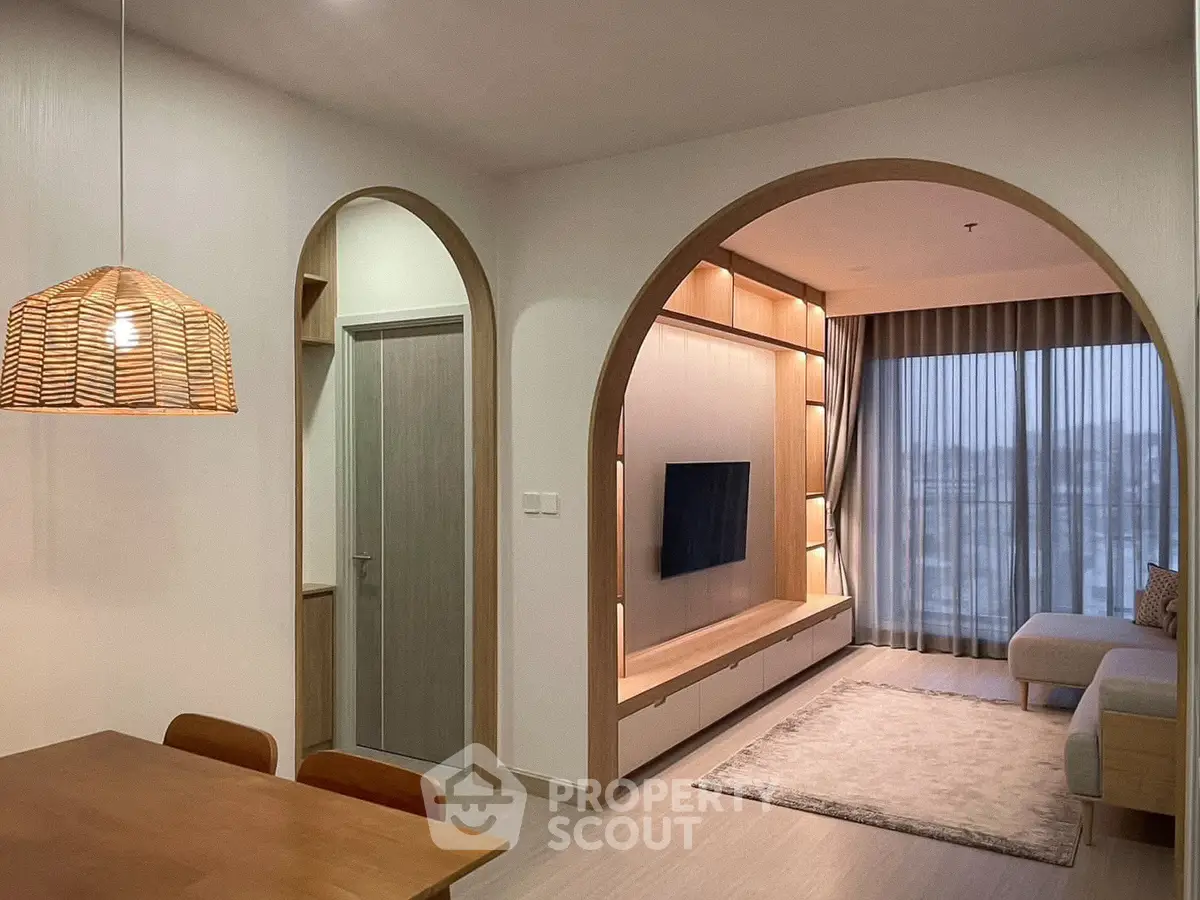 Modern living room with archway, cozy seating, and elegant lighting
