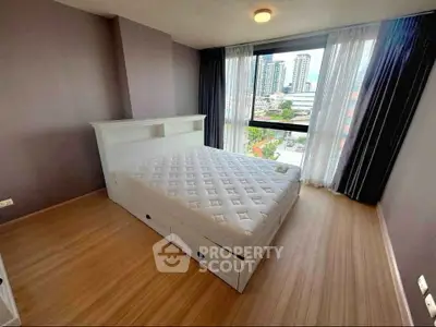 Spacious bedroom with city view, featuring a comfortable bed and large window for natural light.