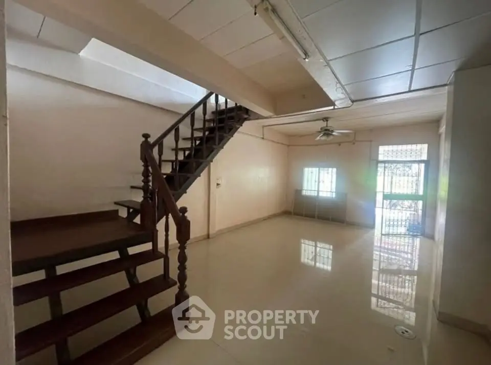 Spacious living room with staircase and large windows in a modern home.