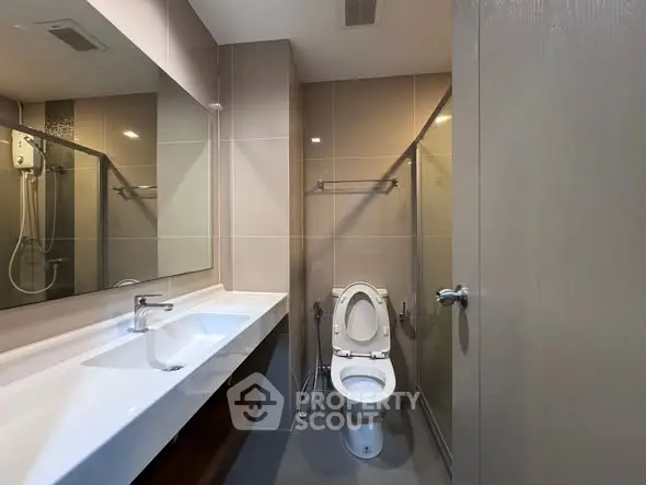 Modern bathroom with sleek fixtures and spacious layout, featuring a large mirror and elegant design.