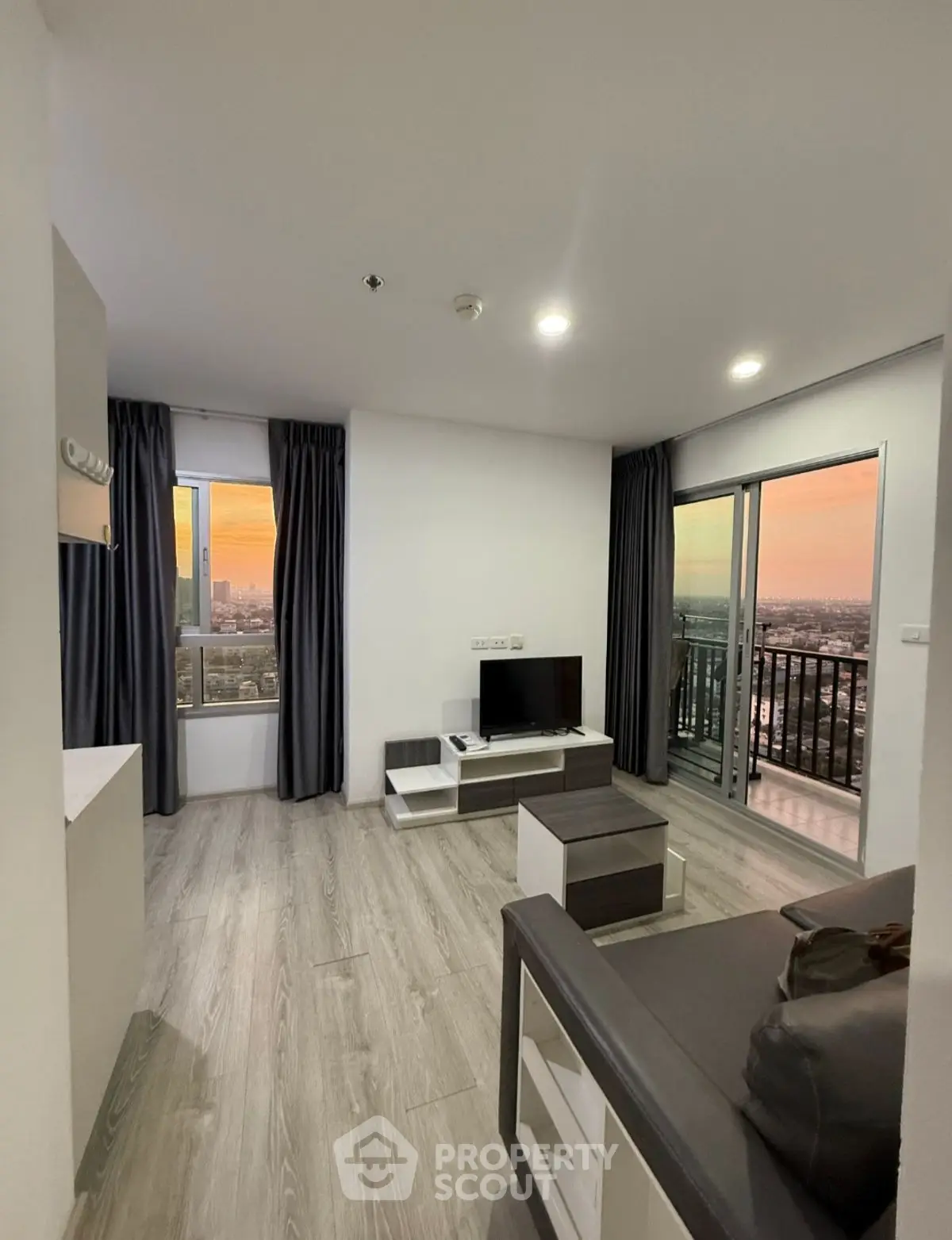 Modern living room with city view and balcony access at sunset