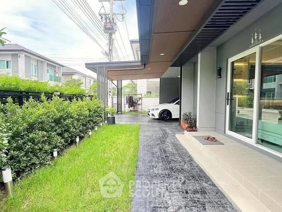 Modern home exterior with lush garden and sleek driveway in suburban setting.
