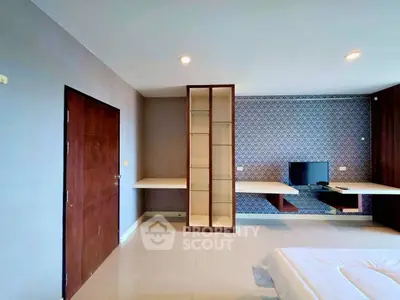 Modern bedroom with built-in shelving and stylish wallpaper accent wall.