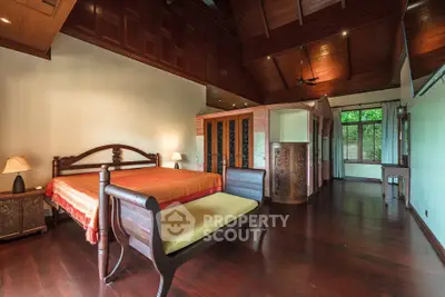 Luxurious bedroom with elegant wooden furniture and high ceilings in a serene setting.
