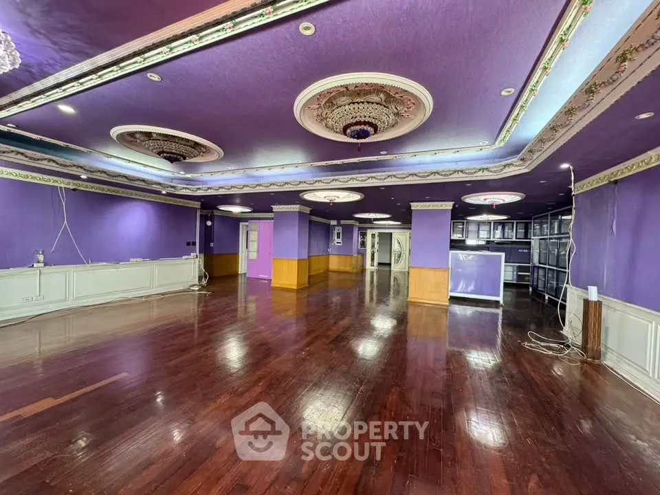 Spacious purple-themed interior with elegant ceiling decor and wooden flooring