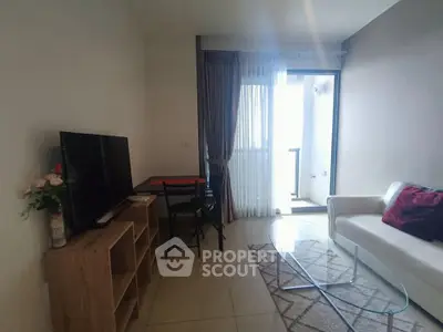 Modern living room with glass coffee table and balcony access, featuring a cozy sofa and TV setup.
