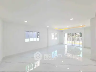 Spacious and bright living room with large windows and glossy marble floors.