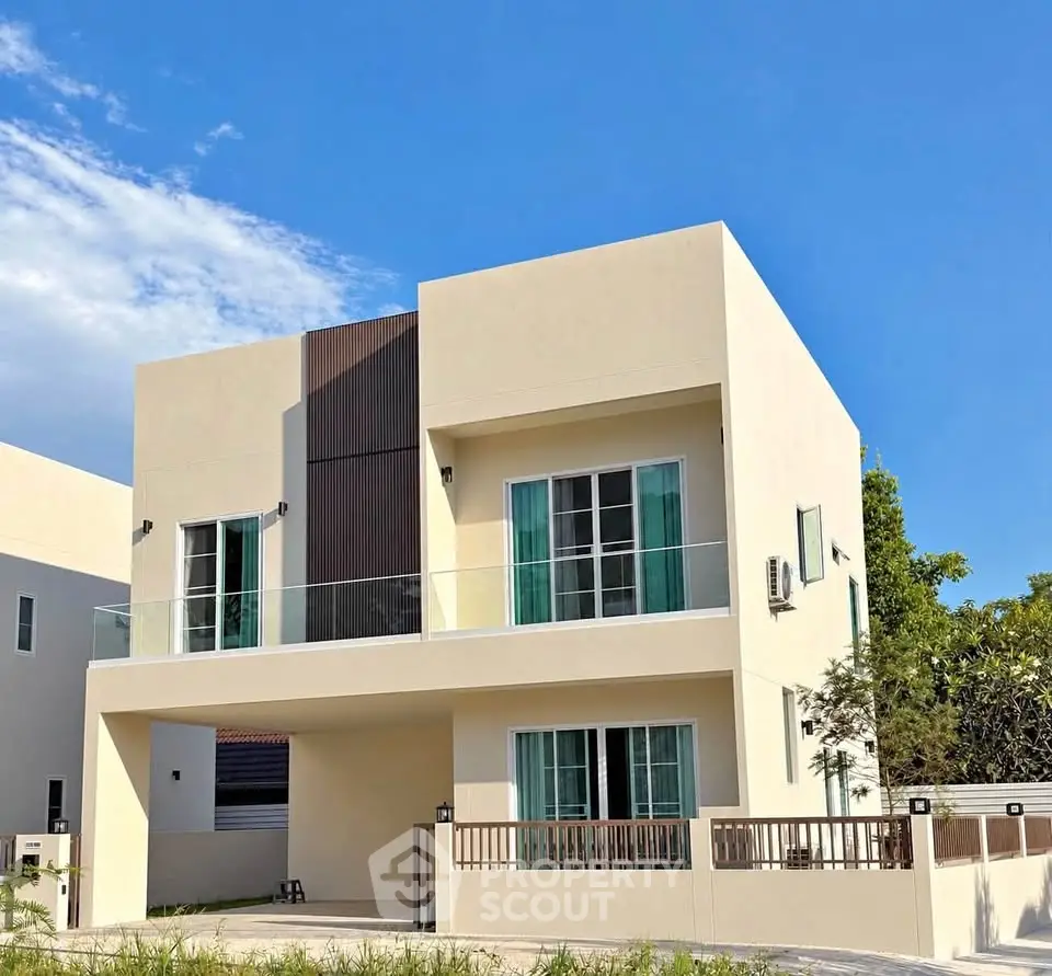 Modern two-story house with minimalist design and large windows under a clear blue sky.