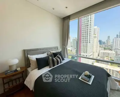 Modern bedroom with city view, featuring stylish decor and large windows for natural light.