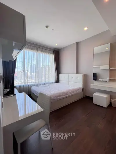 Modern bedroom with city view, featuring sleek furniture and large window for natural light.