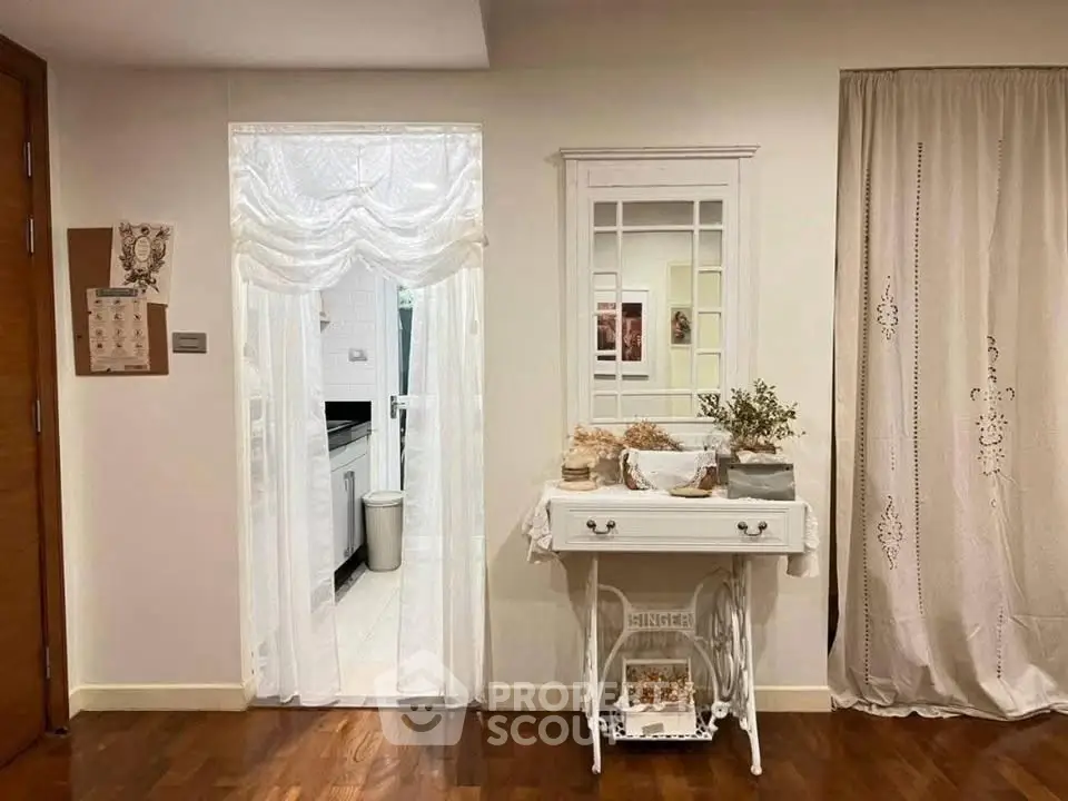 Charming interior with vintage decor and hardwood floors leading to a bright kitchen.