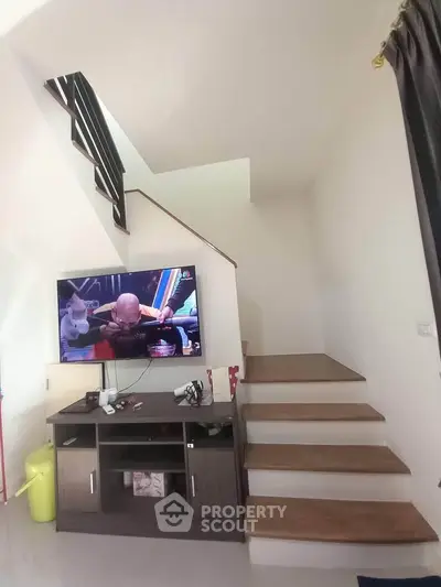 Modern interior with stylish staircase and entertainment unit in a cozy living space.