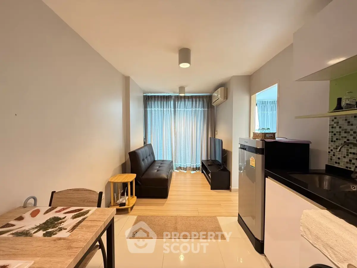 Modern living room with sleek furniture and open kitchen layout in a cozy apartment.