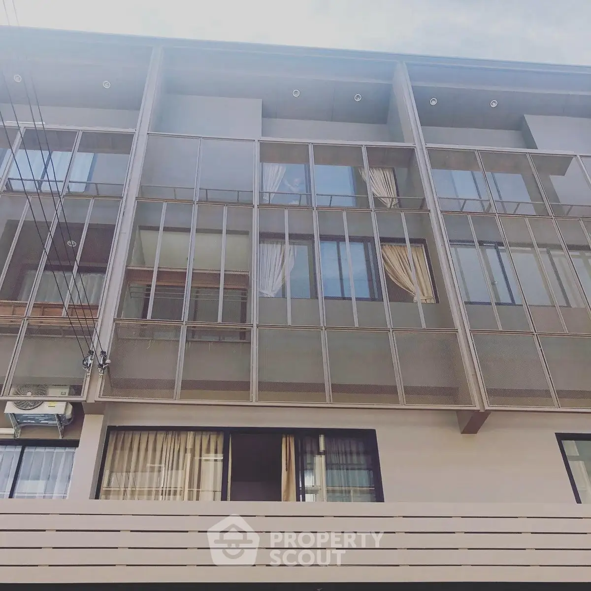 Modern multi-story building exterior with large windows and sleek design.