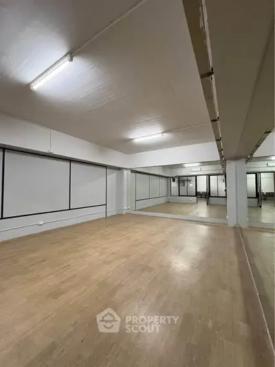 Spacious dance studio with mirrored walls and wooden flooring, ideal for fitness classes or rehearsals.