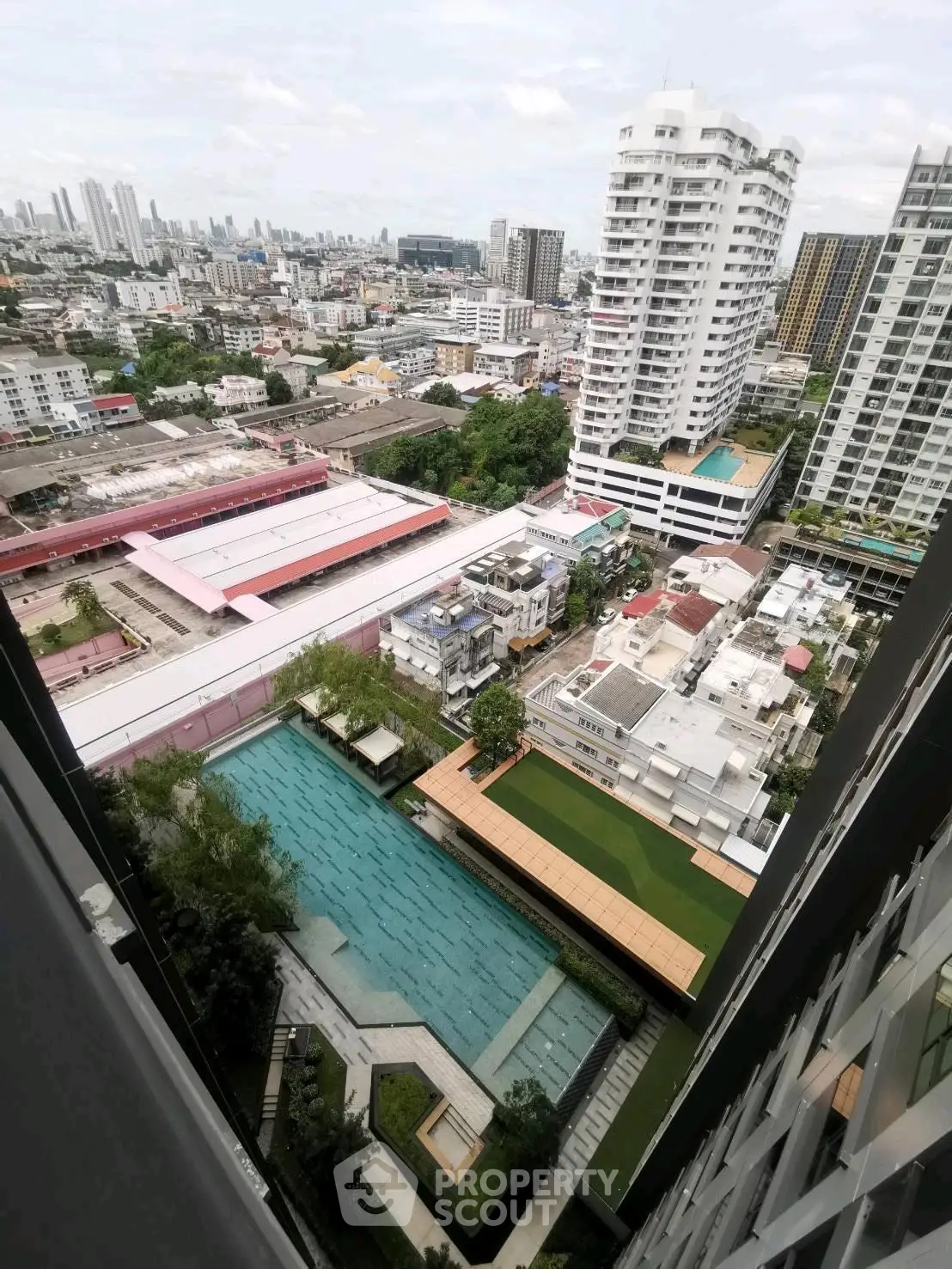 Stunning aerial view of urban residential area with luxurious pool and cityscape backdrop.