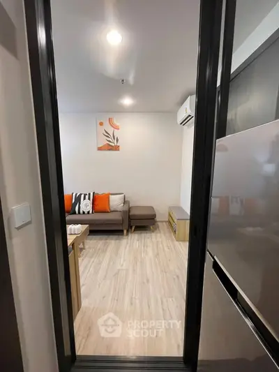 Modern living room with stylish decor and air conditioning, featuring a cozy sofa and wooden flooring.