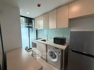 Modern kitchen with sleek cabinetry, washing machine, and microwave in a compact layout.