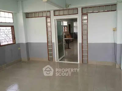 Spacious empty room with tiled floor and large windows, ideal for customization.