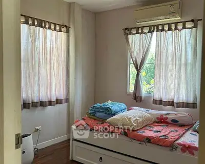 Cozy bedroom with natural light and air conditioning, featuring a comfortable bed and wooden flooring.