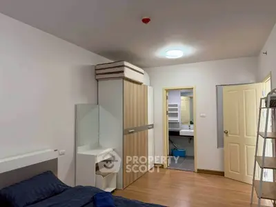Spacious bedroom with modern design and ensuite bathroom, featuring wooden flooring and ample storage space.