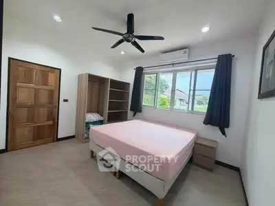 Spacious bedroom with large window and ceiling fan in modern home