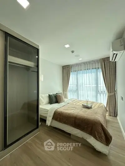 Modern bedroom with large window, stylish decor, and built-in wardrobe in a contemporary apartment.