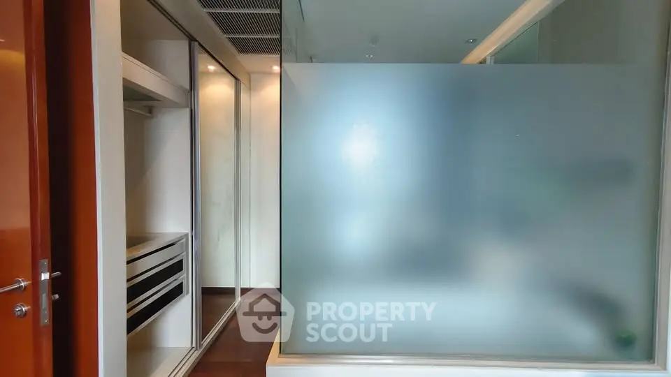 Modern interior with frosted glass partition and sleek closet design