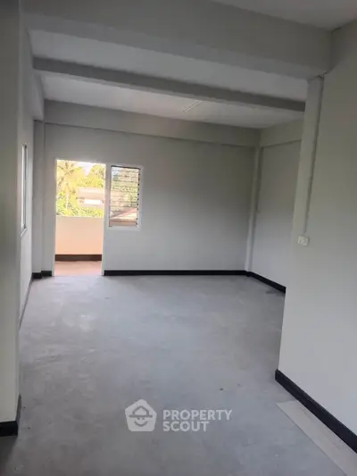 Spacious empty room with balcony access and natural light, ideal for customization.