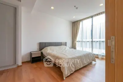 Spacious bedroom with large window and wooden flooring in modern apartment