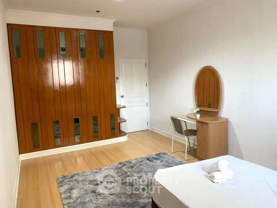 Spacious bedroom with wooden wardrobe and cozy rug
