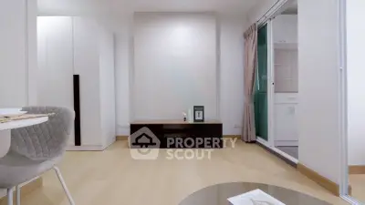 Modern minimalist living room with light wood flooring and sleek furniture, adjacent to a compact kitchen.