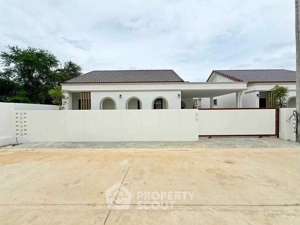 Modern white single-story house with gated entrance and tiled roof