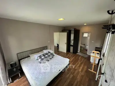 Spacious bedroom with modern decor and ensuite bathroom in a stylish home.