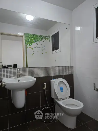 Modern bathroom with sleek fixtures and large mirror, featuring a clean and minimalist design.