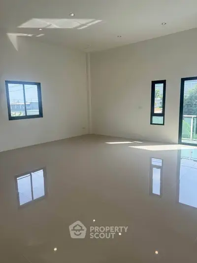 Spacious empty room with glossy tiled floor and large windows offering natural light
