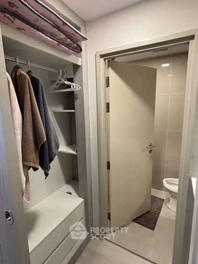 Modern apartment with sleek closet and bathroom, featuring contemporary design and efficient use of space.