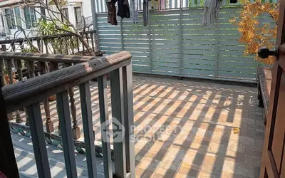 Spacious balcony with wooden railing and privacy screen, perfect for outdoor relaxation.